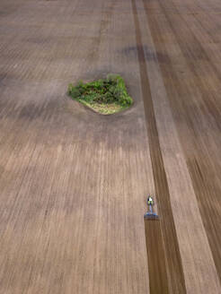 Russland, Region Moskau, Luftaufnahme eines Traktors auf einem landwirtschaftlichen Feld mit Bäumen - KNTF04609