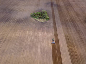 Russland, Region Moskau, Luftaufnahme eines Traktors auf einem landwirtschaftlichen Feld mit Bäumen - KNTF04610