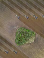 Russia, Moscow region, Aerial view of tractors on agricultural field and trees - KNTF04614