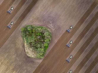 Russia, Moscow region, Aerial view of tractors on agricultural field and trees - KNTF04615