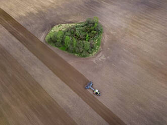 Russia, Moscow region, Aerial view of tractor on agricultural field and trees - KNTF04616