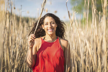 Portrait of happy young woman among reed - ASCF01340