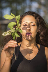 Porträt einer jungen Frau mit geschlossenen Augen, die einen Zweig hält - ASCF01346
