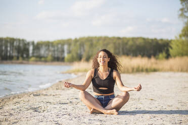 Porträt einer jungen Frau bei einer Yogaübung am Strand - ASCF01347
