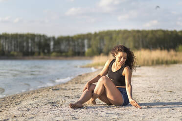 Glückliche junge Frau beim Entspannen am Strand - ASCF01349