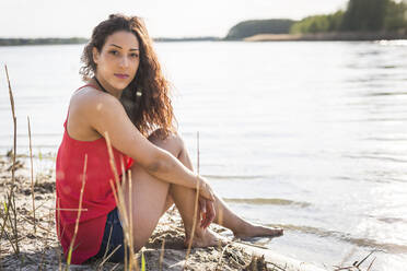 Porträt einer jungen Frau, die am Seeufer sitzt - ASCF01367
