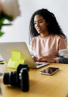 Junge Frau arbeitet von zu Hause aus am Laptop - MGOF04298