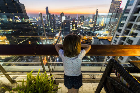 Mädchen mit Blick auf die Skyline von Bangkok in der Abenddämmerung, Thailand - GIOF08185