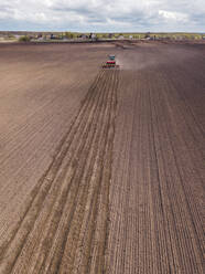 Russia, Aerial view of tractor plowing brown field - KNTF04638