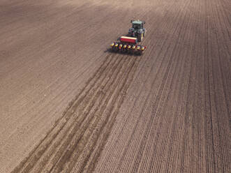 Russia, Aerial view of tractor plowing brown field - KNTF04639