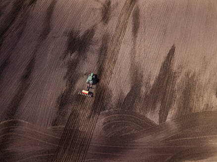 Russland, Luftaufnahme eines Traktors, der ein braunes Feld pflügt - KNTF04641