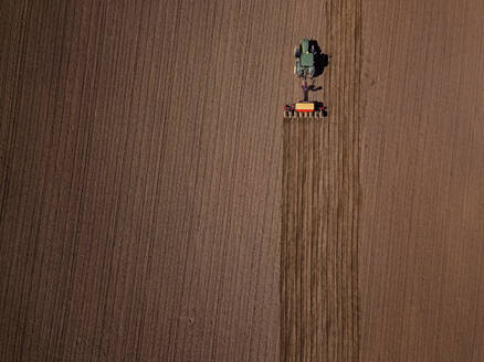Russland, Luftaufnahme eines Traktors, der ein braunes Feld pflügt - KNTF04642