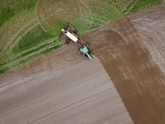 Russia, Aerial view of tractor plowing brown field - KNTF04643