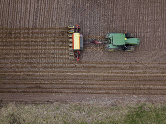 Russia, Aerial view of tractor plowing brown field - KNTF04648