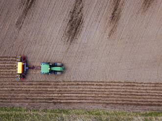 Russia, Aerial view of tractor plowing brown field - KNTF04649