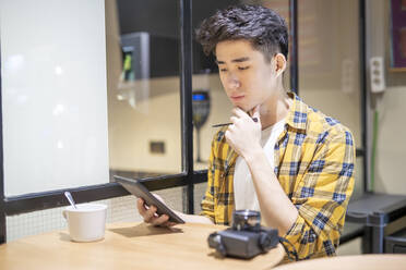 Porträt eines jungen Touristen, der in einer Herberge sein Smartphone benutzt - JCZF00070