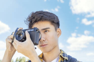 Porträt eines jungen Mannes, der mit einer Kamera fotografiert - JCZF00076