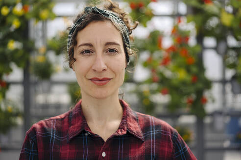 Portrait of confident woman in front of flowers in a gardening shop - JOSEF00689