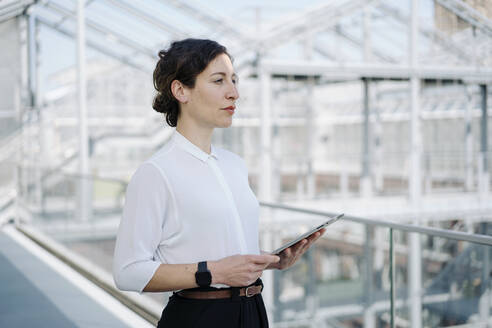 Businesswoman holding tablet looking sideways - JOSEF00706