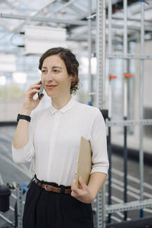 Smiling businesswoman with clipboard on the phone - JOSEF00728