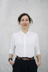 Portrait of a smiling businesswoman at a concrete wall - JOSEF00731