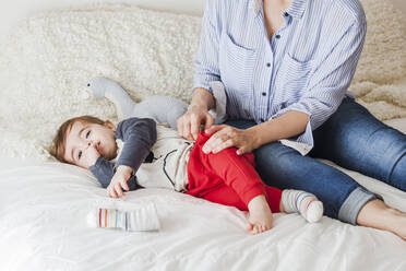 crop view of mother sitting on bed playing with her little son - FLMF00222