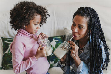 Mutter und ihre kleine Tochter trinken Smoothies zu Hause - EBBF00081