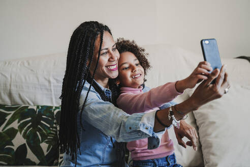 Glückliche Mutter und ihre kleine Tochter nehmen Selfie mit Smartphone zu Hause - EBBF00083