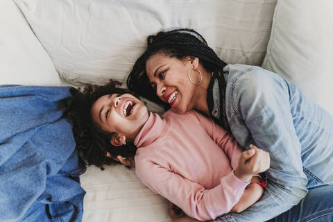 Mutter und kleine Tochter auf der Couch zu Hause und haben Spaß, lizenzfreies Stockfoto