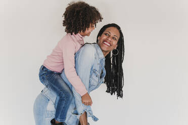 Portrait of happy mother giving her little daughter a piggyback ride - EBBF00094