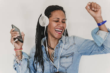 Portrait of dancing woman listening music with headphones and smartphone - EBBF00095