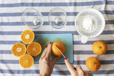 Frau schneidet frische Orangen für frisch gepressten Orangensaft - WPEF02895