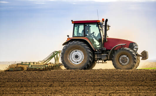 Farmer in tractor plowing field in spring - NOF00089