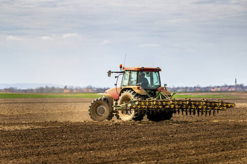 Landwirt im Traktor pflügt Feld im Frühling, lizenzfreies Stockfoto