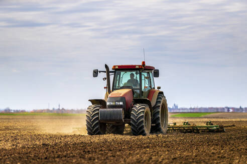 Farmer in tractor plowing field in spring - NOF00091