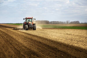 Farmer in tractor plowing field in spring - NOF00093