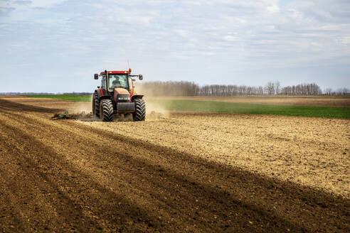 Landwirt im Traktor pflügt Feld im Frühling - NOF00093