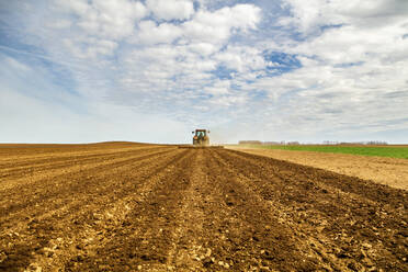 Farmer in tractor plowing field in spring - NOF00095
