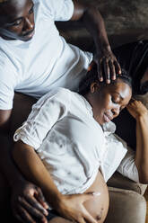 Zärtlicher Mann mit schwangerer junger Frau auf der Couch - OCMF01233