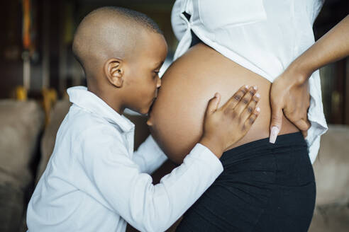 Kleiner Junge küsst den Bauch einer schwangeren jungen Frau - OCMF01235