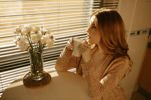 Blonde Frau, die morgens in der Küche Kaffee trinkt, lizenzfreies Stockfoto