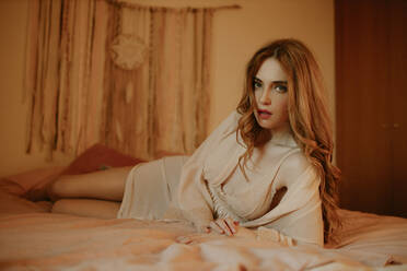 Porträt einer attraktiven blonden Frau, die zu Hause im Bett liegt - GMLF00211
