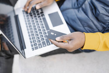 Nahaufnahme eines Mannes, der einen Laptop und eine Kreditkarte zum Online-Shopping benutzt - JCZF00083