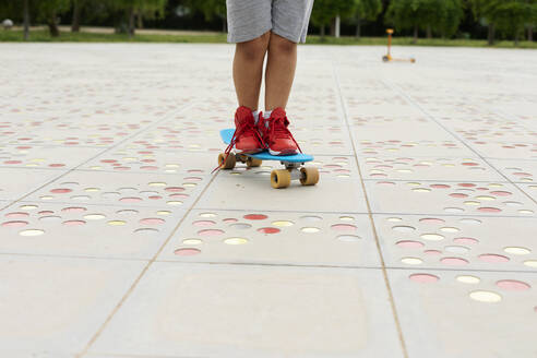 Crop-Ansicht eines Jungen, der auf einem Skateboard steht - VABF02974