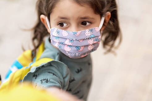 Girl with mask holding father's hand outdoors - EGAF00108