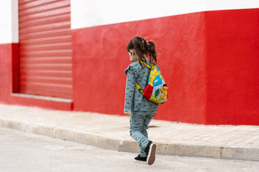 Girl walking with backpack and mask on street - EGAF00113