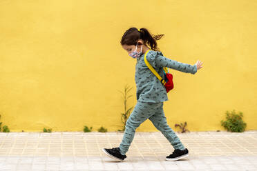 girl walking with backpack and mask outdoors - EGAF00114