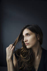 Porträt einer träumenden jungen Frau vor grauem Hintergrund - JOSEF00746