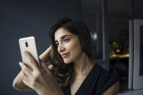 Porträt einer lächelnden jungen Frau, die ein Selfie mit ihrem Smartphone macht, lizenzfreies Stockfoto