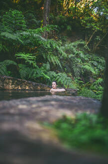 Junge Frau beim Baden in einer heißen Quelle, Caldeira Velha, Insel Sao Miguel, Azoren, Portugal - FVSF00280